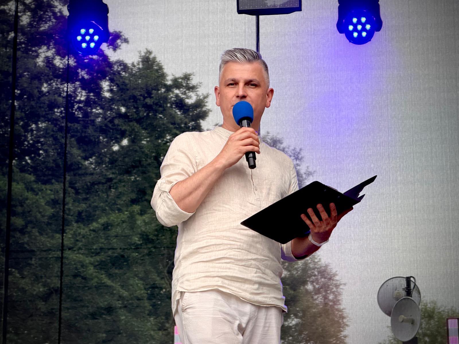 Prowadzący wydarzenie z mikrofonem i notatnikiem na scenie
